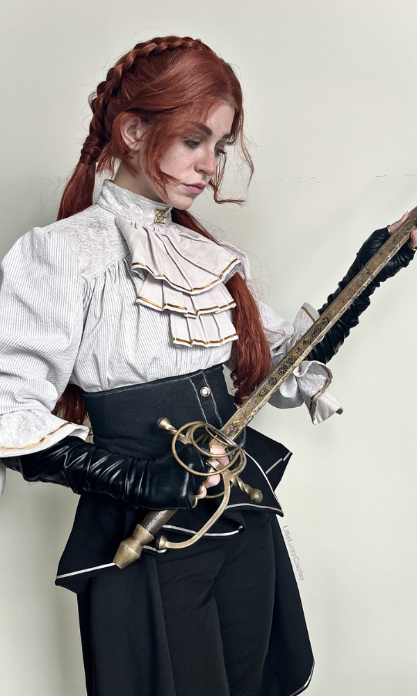 Cosplayer portraying Maelle from Clair Obscur: Expedition 33, wearing a Victorian-inspired outfit and holding an ornate rapier, reflecting the character’s elegance and combat readiness.